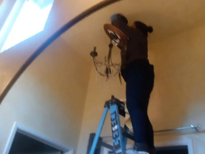 Electrician installing a chandelier in a Los Chaves residence